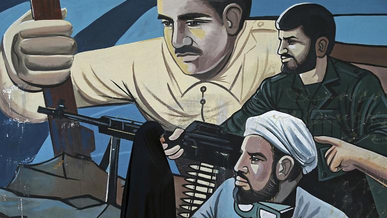 A woman walks past of a mural depicting members of Iran's Basij volunteer paramilitary force, in downtown Tehran, Iran   -   کپی رایت  AP Photo